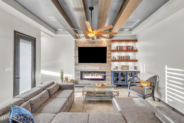 living room featuring beam ceiling, a stone fireplace, and ceiling fan