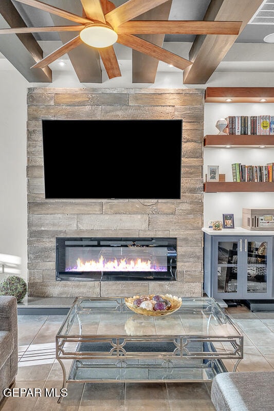 details with beamed ceiling, ceiling fan, and a stone fireplace