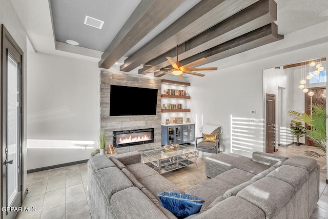 living room with ceiling fan, a large fireplace, beamed ceiling, and light tile patterned floors