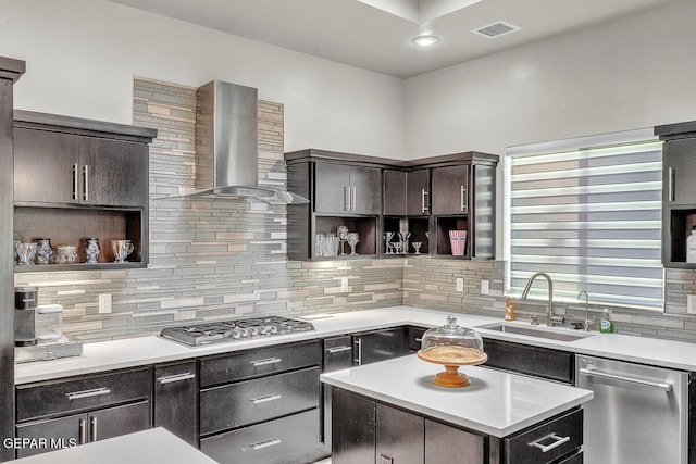 kitchen with a center island, wall chimney range hood, sink, appliances with stainless steel finishes, and tasteful backsplash