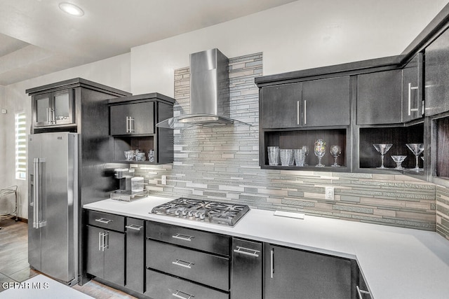 kitchen featuring stainless steel appliances, tasteful backsplash, wall chimney exhaust hood, and light hardwood / wood-style floors