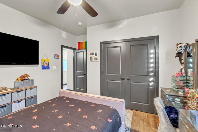 bedroom with a closet, light hardwood / wood-style floors, and ceiling fan