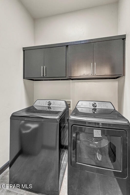 washroom with cabinets and washing machine and clothes dryer