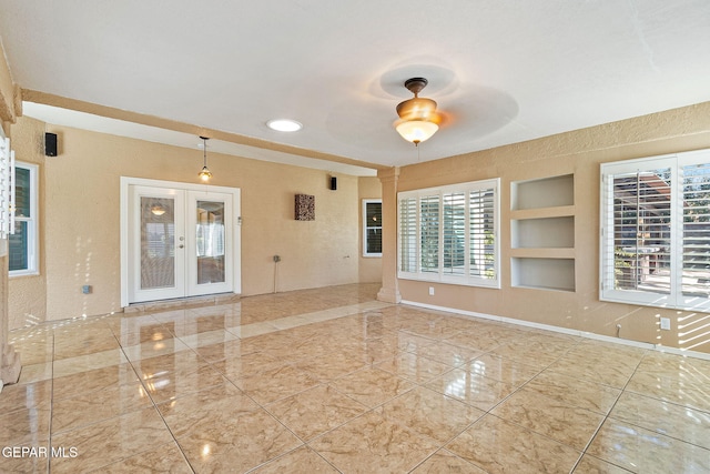 spare room featuring plenty of natural light, ceiling fan, built in features, and french doors