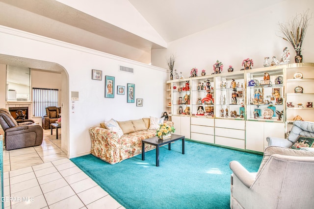 tiled living room featuring a tiled fireplace and vaulted ceiling