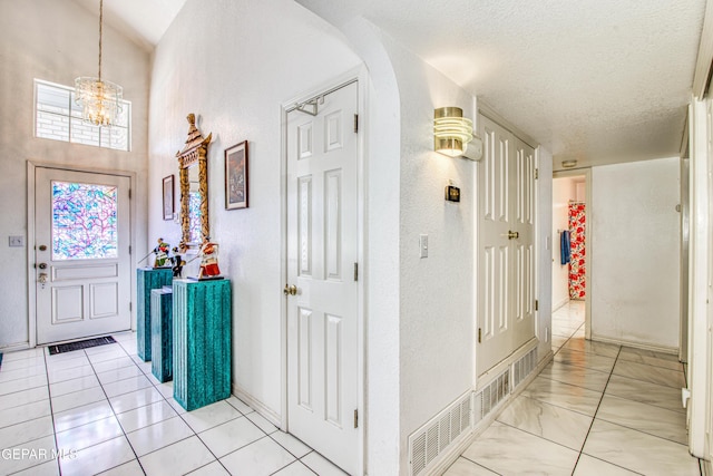 tiled foyer featuring an inviting chandelier and a textured ceiling