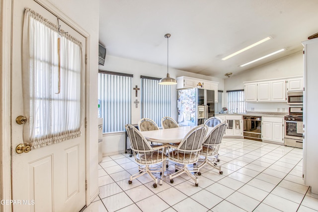 dining space with light tile patterned floors, a healthy amount of sunlight, and vaulted ceiling