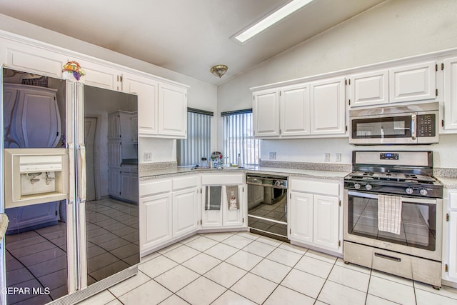 kitchen with appliances with stainless steel finishes, white cabinets, and light tile patterned floors