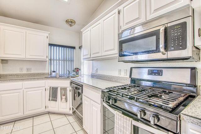 kitchen with stainless steel appliances, sink, white cabinets, lofted ceiling, and light tile patterned flooring