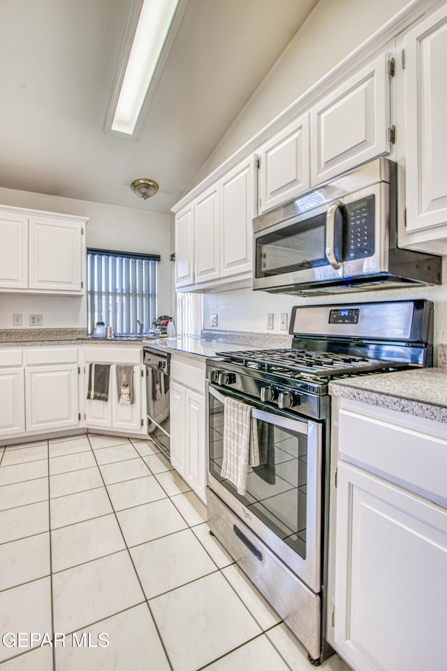 kitchen with appliances with stainless steel finishes, white cabinets, and light tile patterned floors