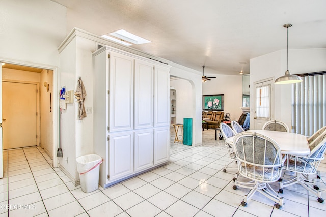 dining room with ceiling fan, light tile patterned flooring, and vaulted ceiling with skylight