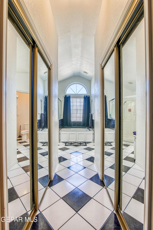 hallway with tile patterned flooring and vaulted ceiling