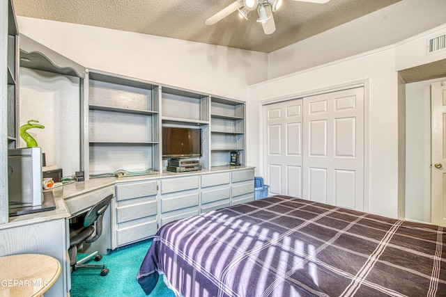 bedroom with a closet, built in desk, carpet floors, ceiling fan, and a textured ceiling