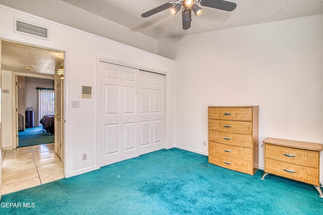 carpeted bedroom with a closet, ceiling fan, and a textured ceiling