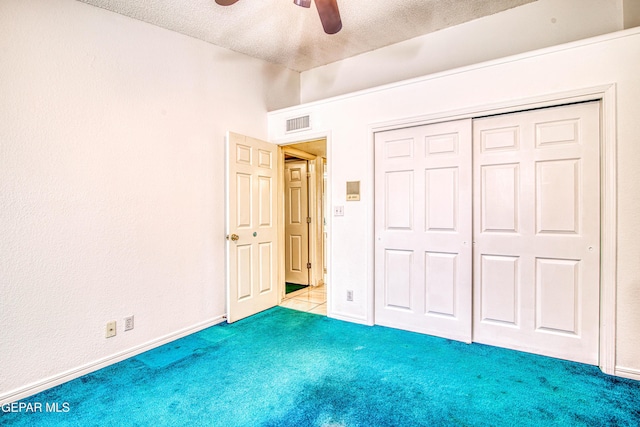 unfurnished bedroom with a closet, light carpet, a textured ceiling, and ceiling fan