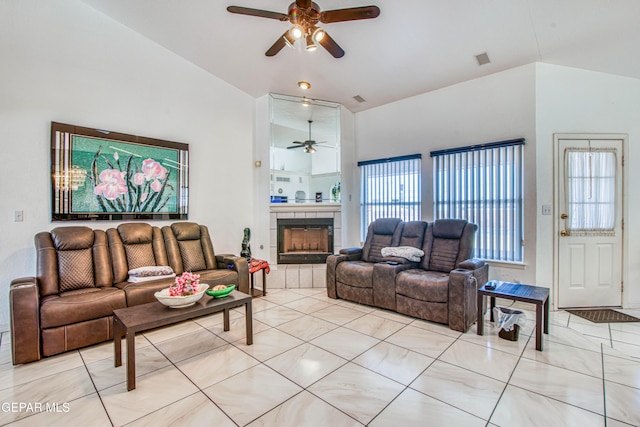 living room with a tiled fireplace, ceiling fan, and vaulted ceiling