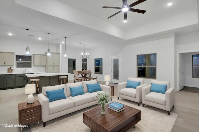living room featuring recessed lighting, light wood-type flooring, baseboards, and ceiling fan with notable chandelier