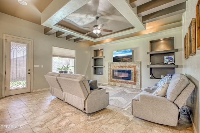 living room with beamed ceiling, built in shelves, ceiling fan, and a tiled fireplace