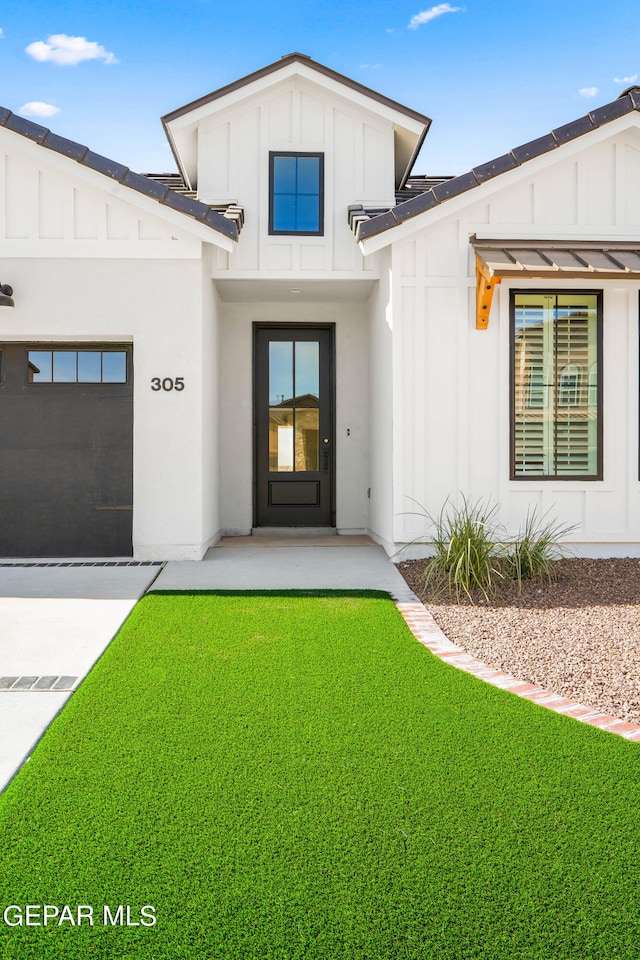 property entrance with a garage and a lawn