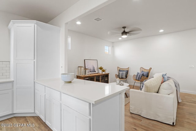 kitchen with kitchen peninsula, light hardwood / wood-style floors, white cabinetry, and ceiling fan