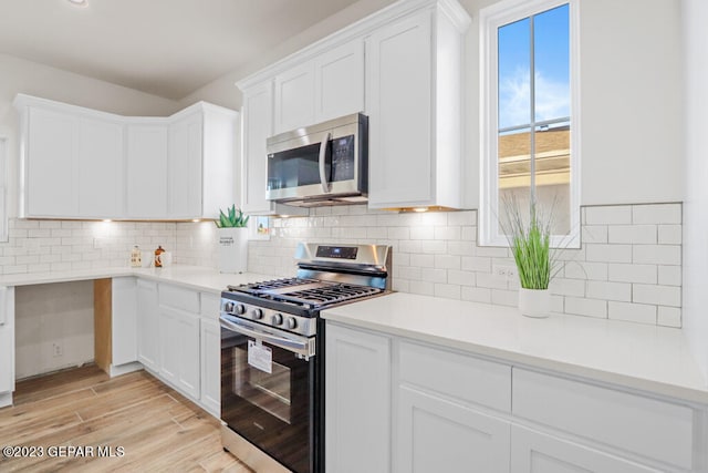 kitchen featuring white cabinets, appliances with stainless steel finishes, backsplash, and light hardwood / wood-style floors