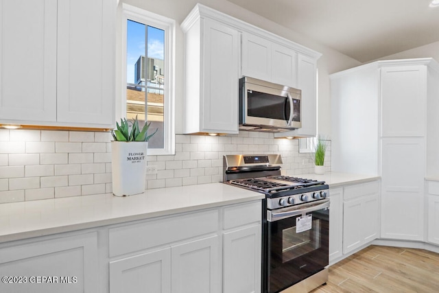 kitchen with white cabinets, stainless steel appliances, light hardwood / wood-style flooring, and tasteful backsplash