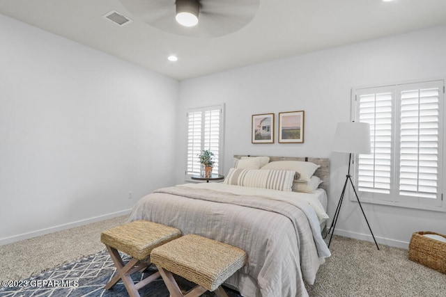 bedroom with ceiling fan, light carpet, and multiple windows