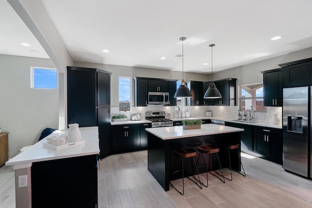 kitchen with a wealth of natural light, a kitchen island, appliances with stainless steel finishes, and light hardwood / wood-style flooring