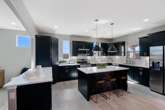 208 Playa Vista St, Horizon City, TX 79928 - kitchen with stainless steel appliances, dark cabinets, a kitchen breakfast bar, decorative backsplash, and recessed lighting