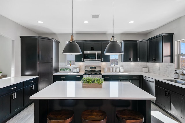 kitchen with a kitchen breakfast bar, stainless steel appliances, a kitchen island, and hanging light fixtures