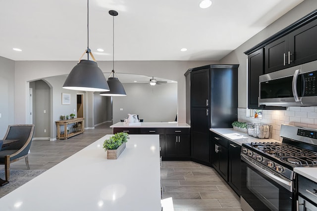 kitchen with ceiling fan, stainless steel appliances, backsplash, decorative light fixtures, and hardwood / wood-style flooring