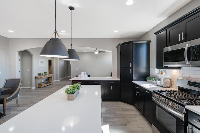 208 Playa Vista St, Horizon City, TX 79928 - kitchen with stainless steel appliances, light countertops, dark cabinets, arched walkways, and recessed lighting