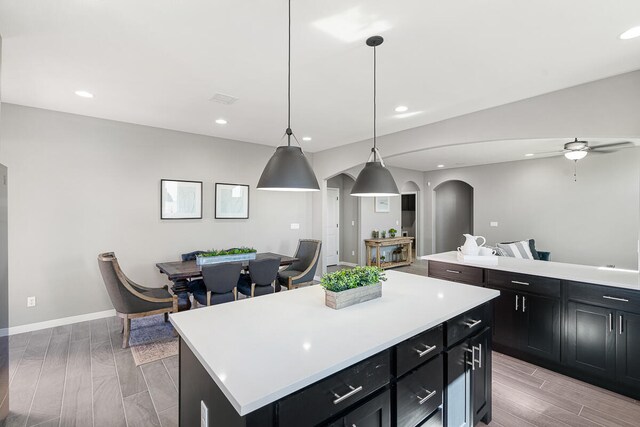 kitchen with ceiling fan, a center island, light hardwood / wood-style floors, and hanging light fixtures