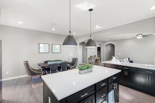 208 Playa Vista St, Horizon City, TX 79928 - kitchen with arched walkways, a kitchen island, wood finish floors, light countertops, and recessed lighting