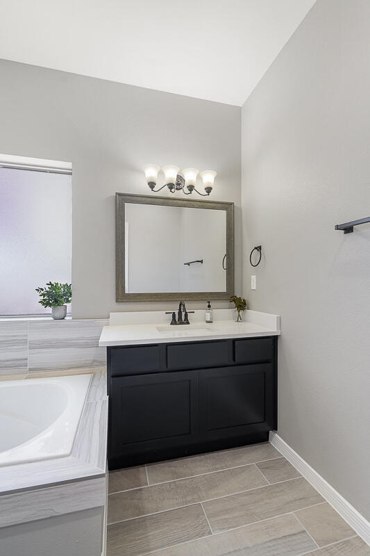 bathroom with a bath, vanity, and vaulted ceiling