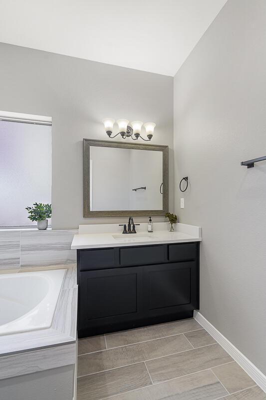 208 Playa Vista St, Horizon City, TX 79928 - bathroom featuring vanity, baseboards, and a garden tub