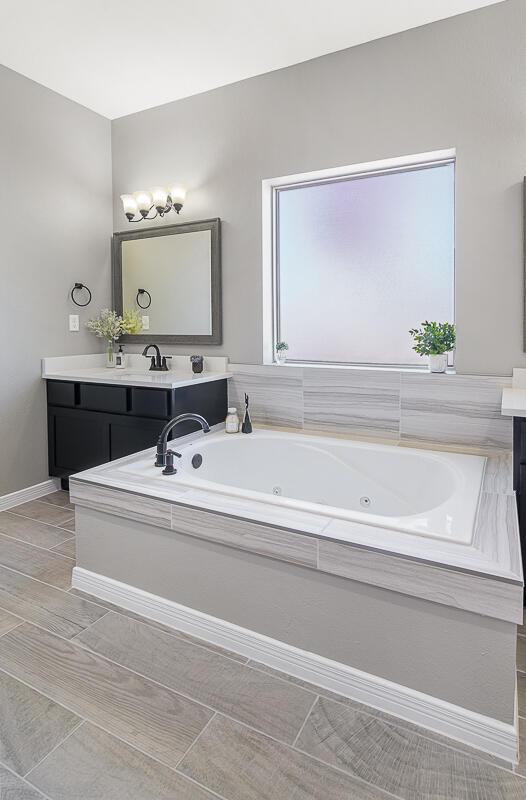 208 Playa Vista St, Horizon City, TX 79928 - bathroom with vanity, a tub with jets, and baseboards
