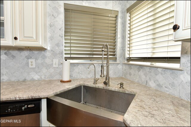 kitchen featuring backsplash, white cabinetry, sink, and stainless steel dishwasher