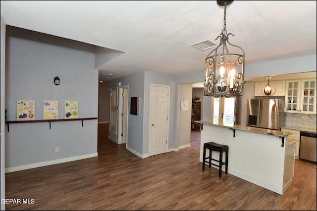 kitchen featuring a breakfast bar, appliances with stainless steel finishes, an inviting chandelier, and dark wood-type flooring