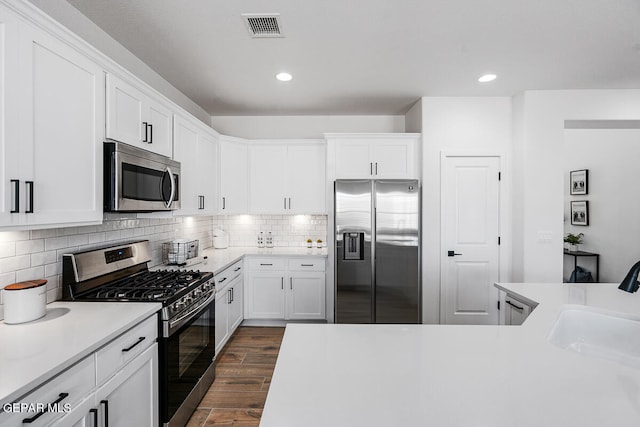 kitchen with backsplash, dark wood-type flooring, sink, appliances with stainless steel finishes, and white cabinetry