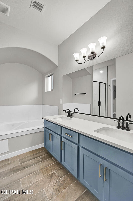 bathroom with a textured ceiling, vanity, shower with separate bathtub, and hardwood / wood-style flooring