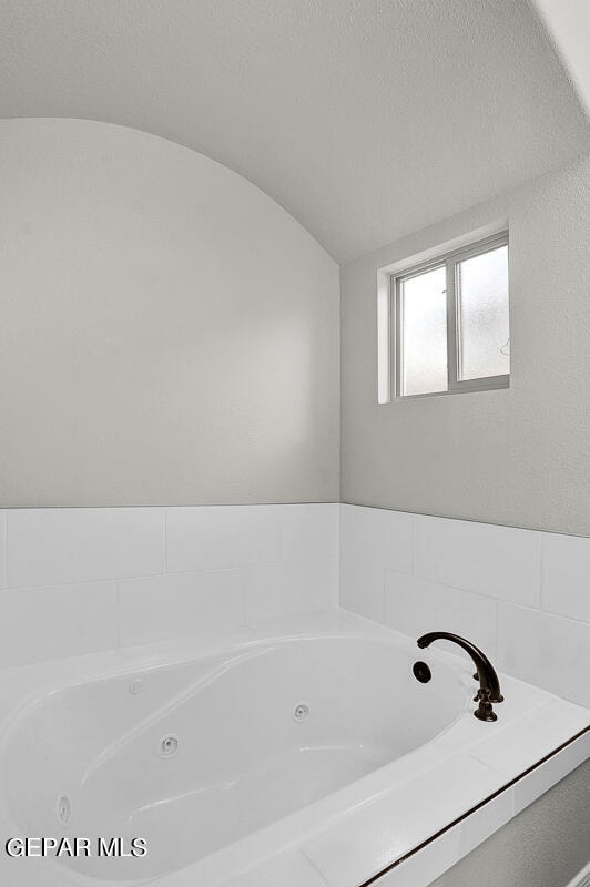 bathroom featuring lofted ceiling, a textured ceiling, and a tub