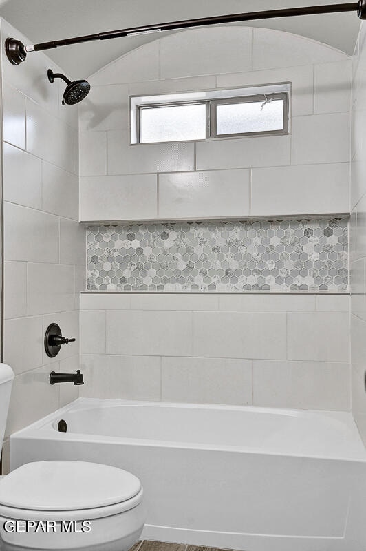 bathroom featuring toilet and tiled shower / bath