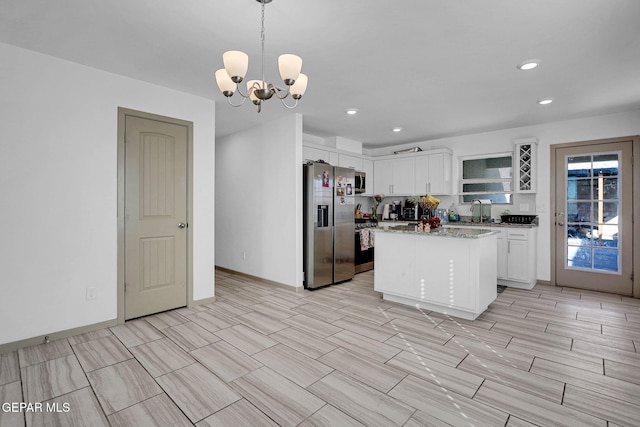 kitchen with white cabinets, hanging light fixtures, a notable chandelier, a kitchen island, and stainless steel appliances