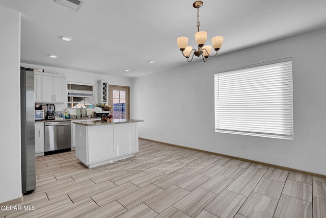 kitchen featuring white cabinetry, sink, stainless steel appliances, a notable chandelier, and pendant lighting