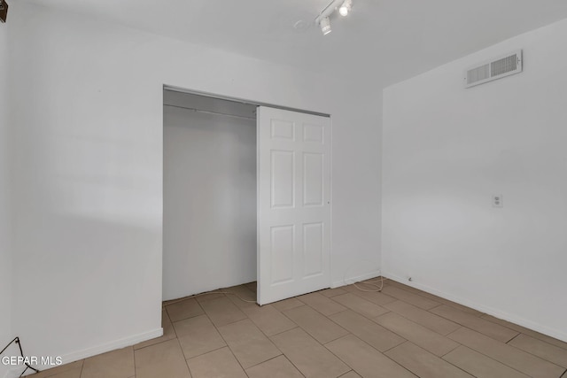 unfurnished bedroom featuring track lighting and a closet