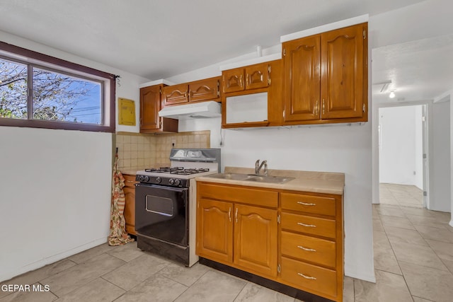 kitchen with light tile patterned flooring, gas stove, tasteful backsplash, and sink