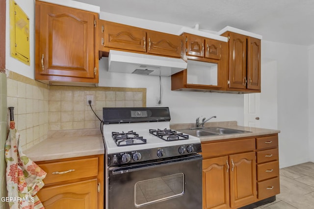 kitchen with gas stove, backsplash, sink, and light tile patterned floors