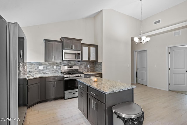 kitchen with a chandelier, high vaulted ceiling, stainless steel appliances, and a kitchen island