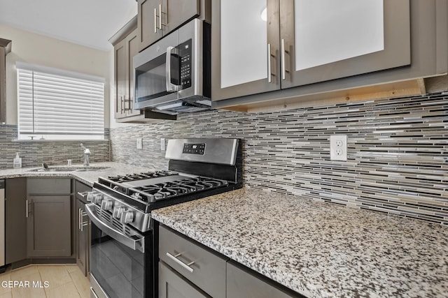 kitchen with light stone countertops, backsplash, stainless steel appliances, sink, and light tile patterned floors